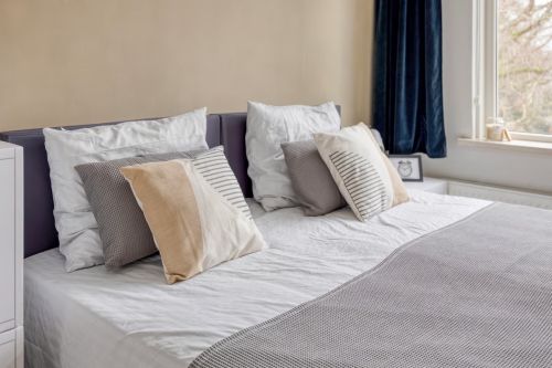 Stijlvolle CUBIQZ-hoofdbordhoes voor een tweepersoonsbed, waarmee een kartonnen bed wordt omgetoverd tot een realistische slaapkamerpresentatie.
